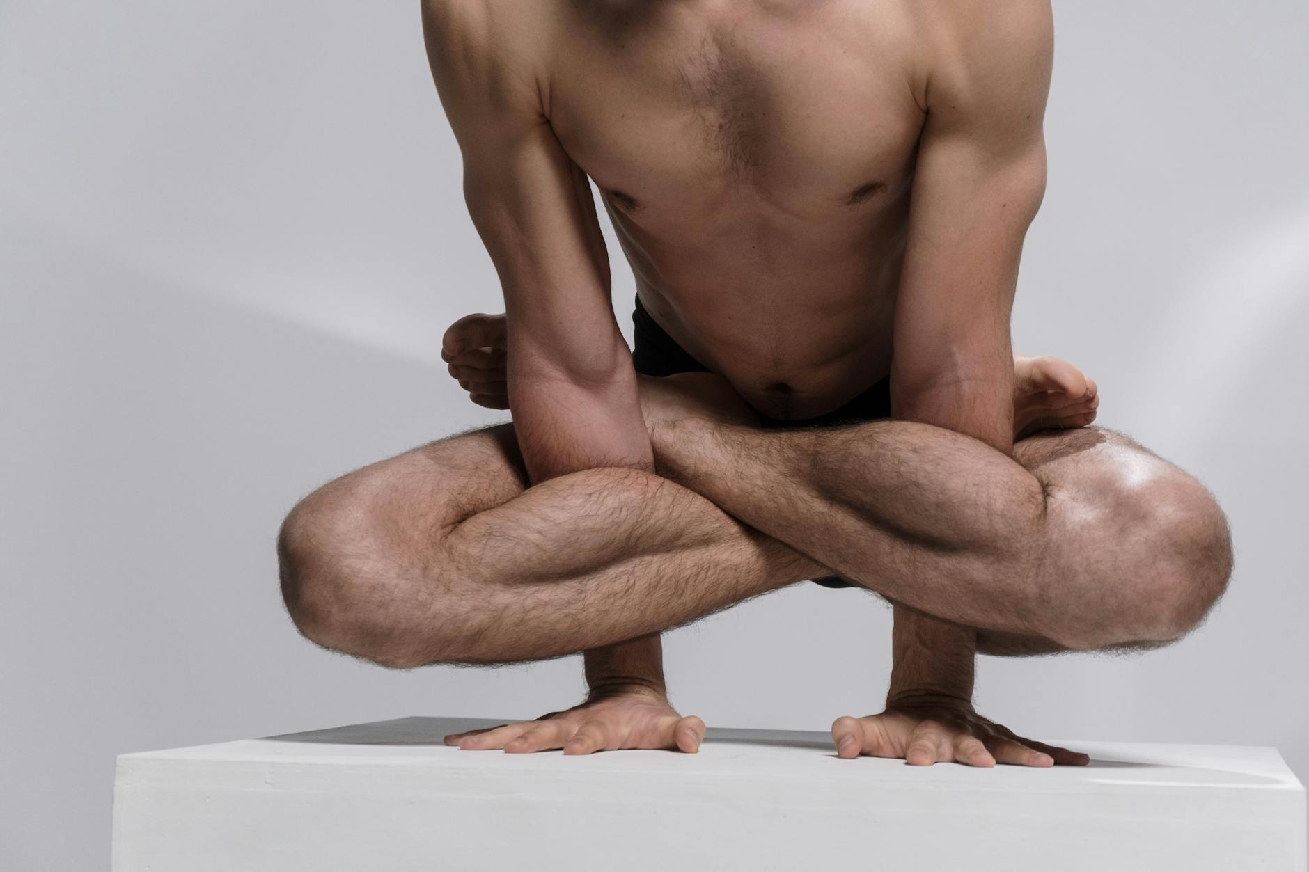 Focused man performing a bodyweight strength exercise in a minimalist studio.